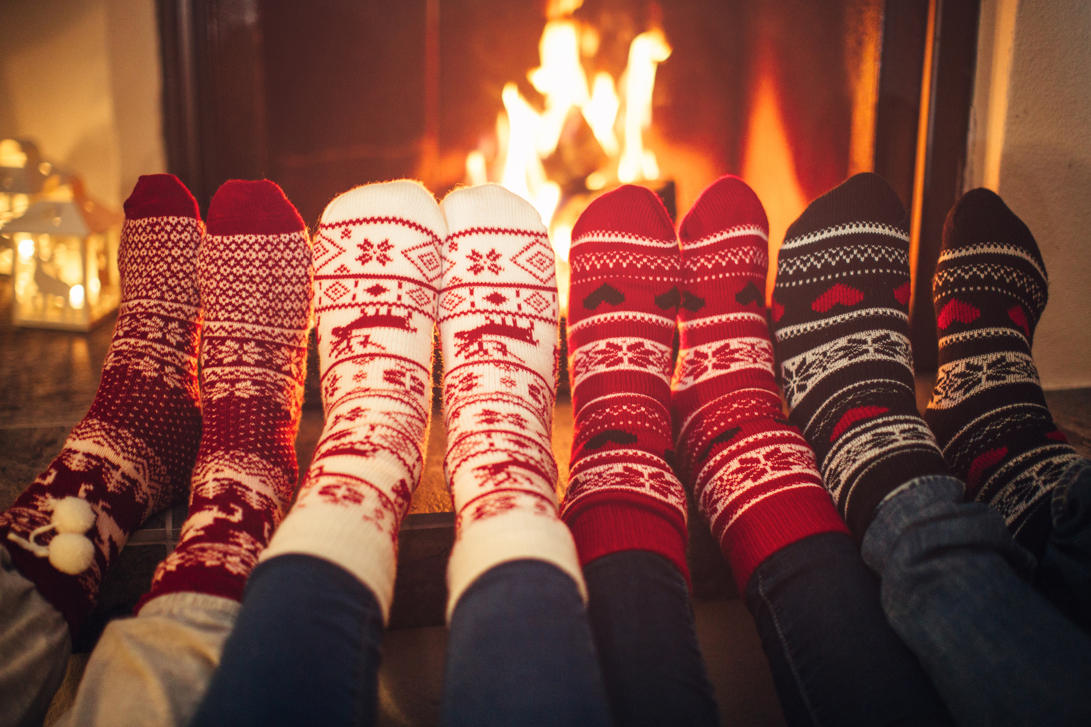 Feet lined up with Christmas socks on fireplace