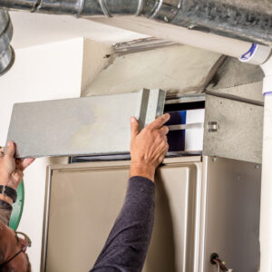 Technician removes the furnace filter cover to inspect