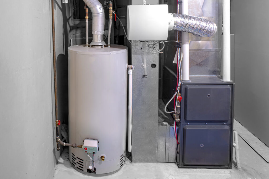 A home high-efficiency furnace with a residential tank gas water heater to the left.