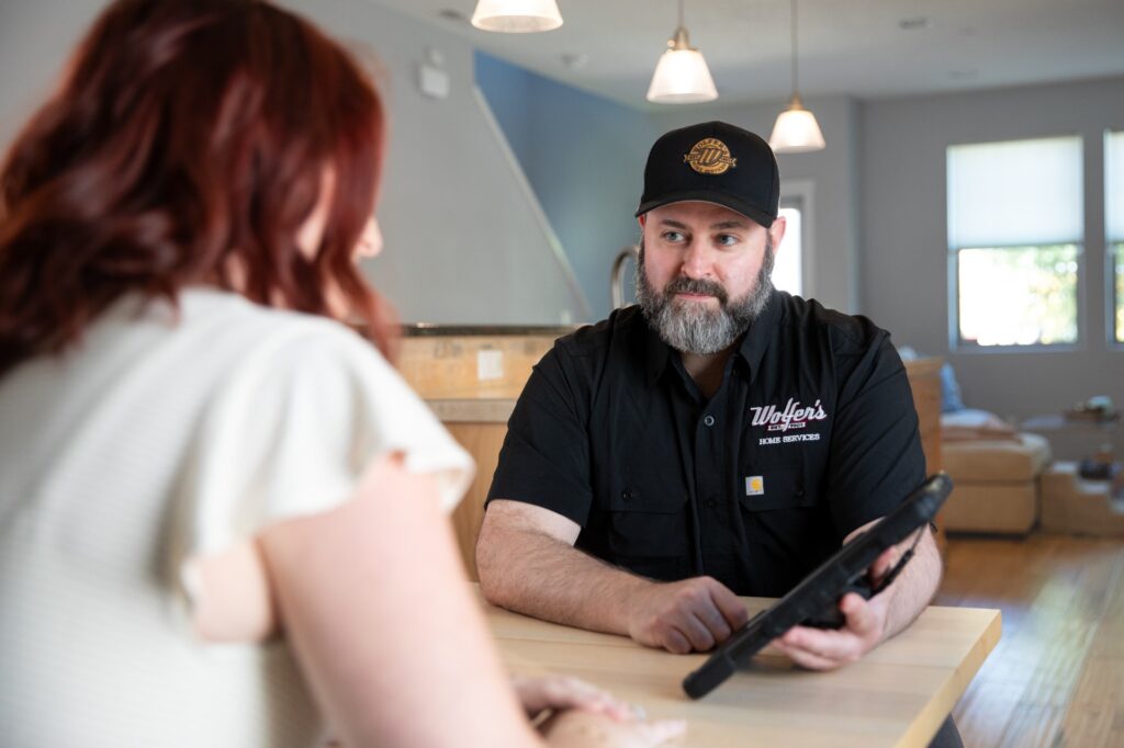 Wolfer's tech talking with customer at their kitchen table.