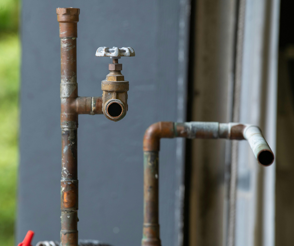 Two outdoor rusty pipes indicating older plumbing system 