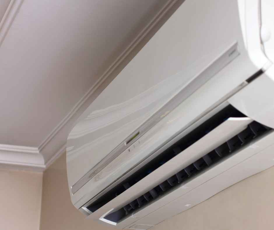 White wall-mounted split AC unit with the front panel open and dark vent louvers visible inside the grill.