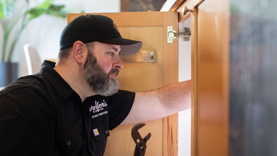 Plumber reaching under the sink to repair garbage disposal.